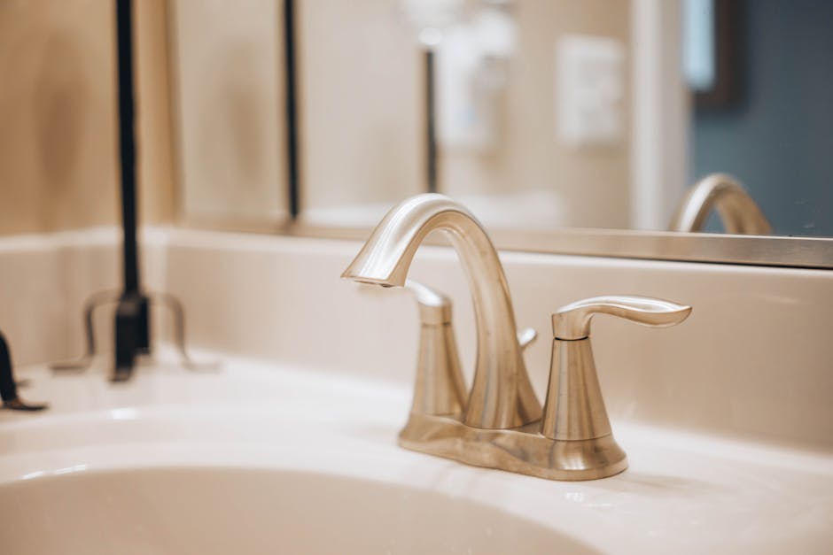 Leaking faucet repair context: sleek modern chrome bathroom faucet on a white ceramic sink showing the typical setup before the leaking faucet teardown