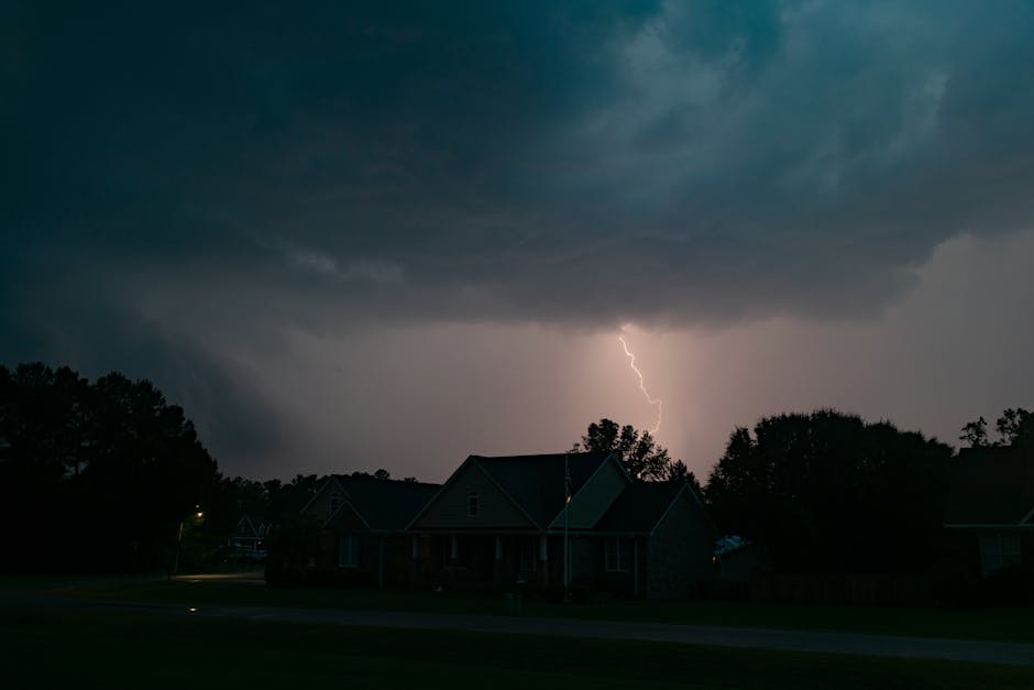 Sump pump not working stress test: a powerful lightning bolt illuminating a suburban neighborhood during a nighttime thunderstorm