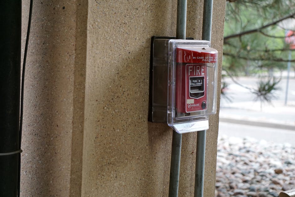 Smoke detector beeping awareness: close-up view of a red fire alarm mounted on a textured outdoor wall, showcasing essential safety equipment for any home