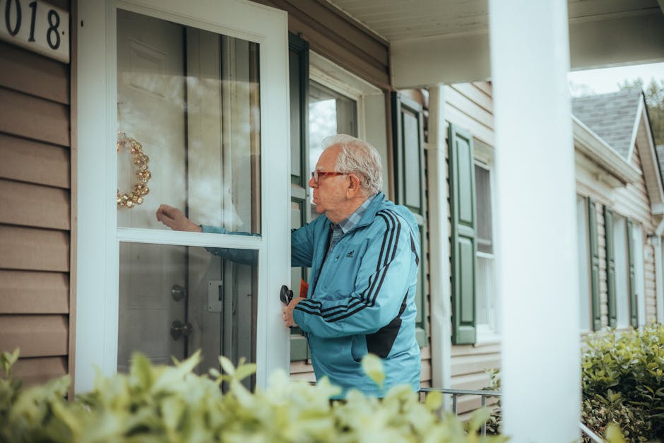 Doorbell not working context: an elderly man in a blue jacket knocking on a suburban house door because the doorbell not working forces visitors to knock