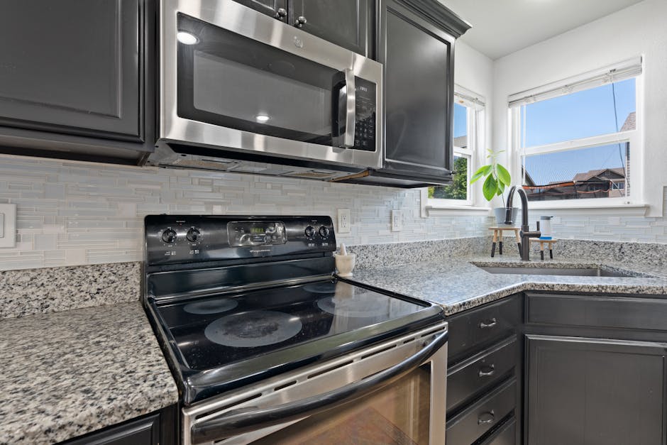 Microwave not heating context: stylish modern kitchen with stainless steel microwave, stove, and granite countertops, showing a typical home setting for this appliance fix