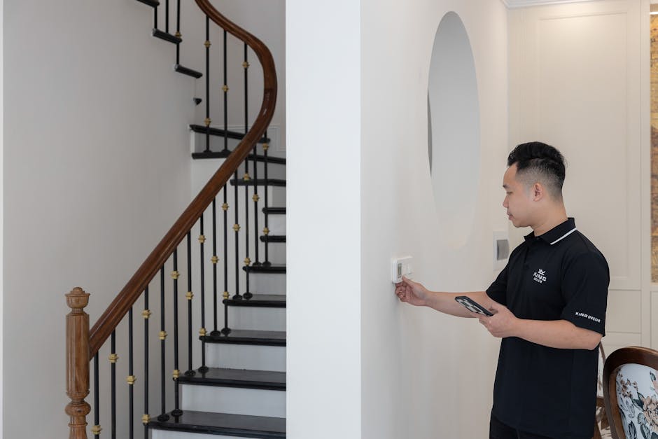 Thermostat not working diagnosis: a man adjusting a wall-mounted thermostat in a stylish home with an elegant staircase