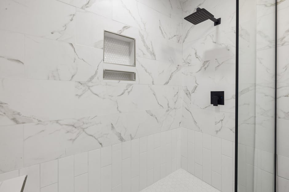 Shower drain smells repair context: sleek shower featuring marble tiles and black fixtures, the typical modern bathroom where a shower drain smells problem hides in the drain assembly under the tile
