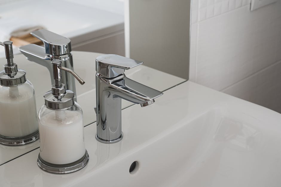 Low water pressure: sleek chrome faucet and soap dispenser on a pristine white sink in a modern bathroom
