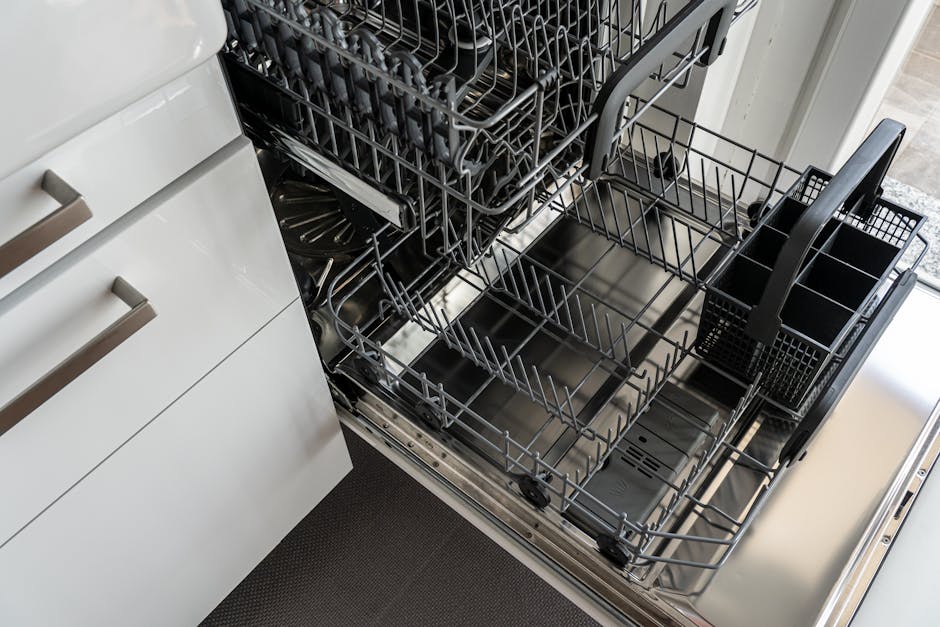Dishwasher leaking at the door gasket: a close-up of an open residential dishwasher door showing the rubber seal around the stainless tub opening and the lower kickplate panel, the typical spot where a dishwasher leaking complaint traces to a food-fouled or flattened gasket
