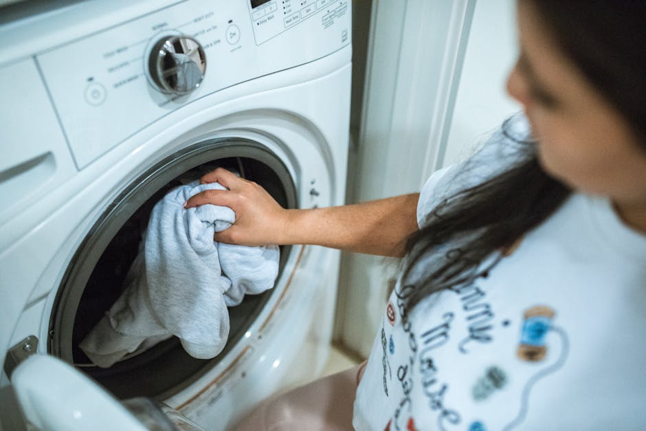 Washer not draining: a woman loading laundry into a washing machine indoors during a household routine
