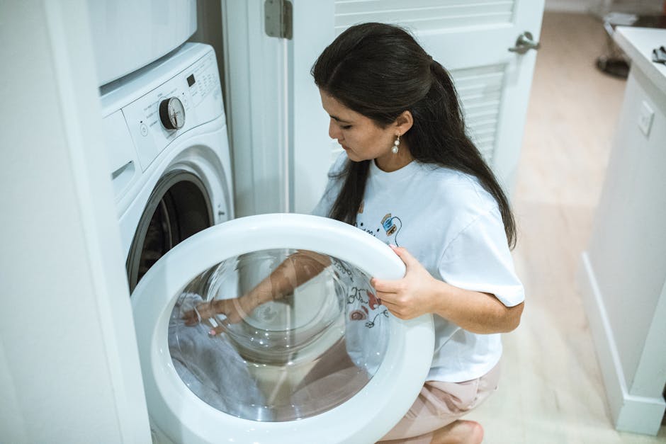 Washer not draining: woman kneeling to load a front-loading washing machine in a modern home laundry room