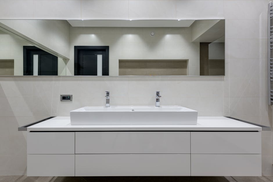 Bathroom sink slow drain vanity context: detailed view of a modern bathroom vanity area with double vessel sinks and a wall mirror, the kind of vanity where a bathroom sink slow drain forces you to clear out the cabinet to reach the P-trap underneath
