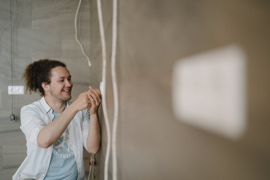 GFCI keeps tripping repair: an electrician with curly hair adjusts a wall outlet indoors, smiling as he works through a GFCI keeps tripping diagnostic