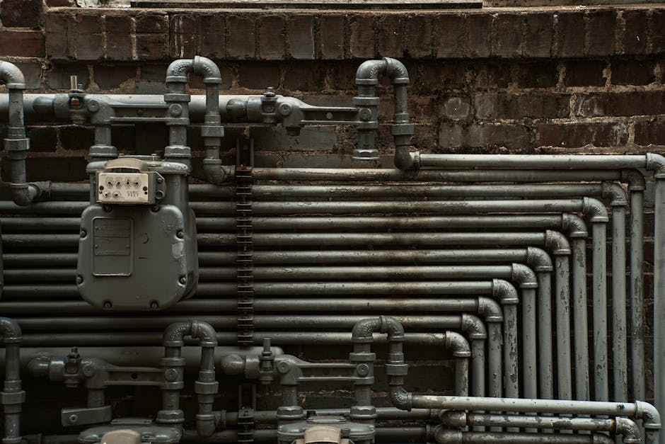 Water hammer prevention context: detailed view of industrial steel pipes mounted on a wall, showing the kind of well-strapped pipe runs that prevent water hammer in residential systems