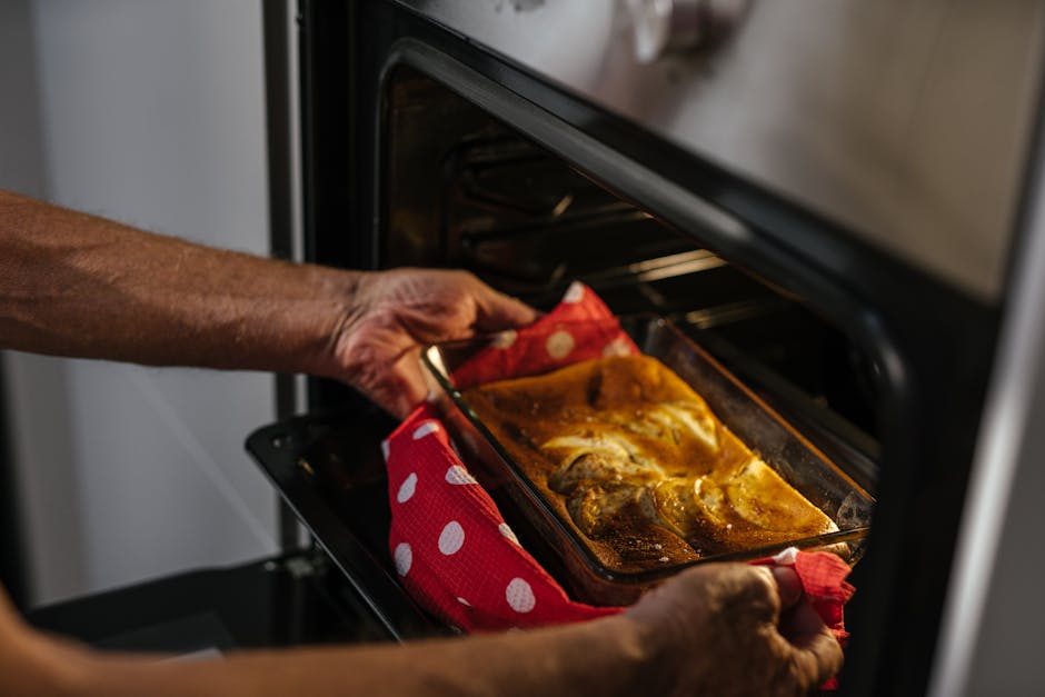 Oven not heating fixed: a person removing a freshly baked golden brown cake from a working home oven, signaling a successful DIY repair