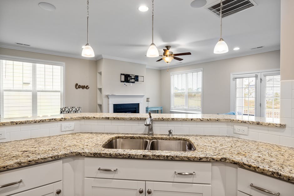 Kitchen light flickering: a bright modern kitchen with recessed ceiling lights and pendant fixtures over an island, the typical layout where a kitchen light flickering complaint shows up the first time someone runs the microwave at the same time