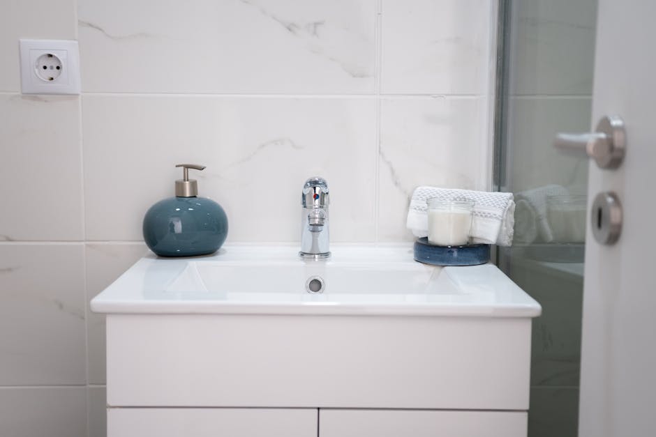 Bathroom sink slow drain: a clean modern white bathroom sink with chrome faucet in a bright bathroom, the typical setup where a bathroom sink slow drain complaint first shows itself as standing water around the stopper