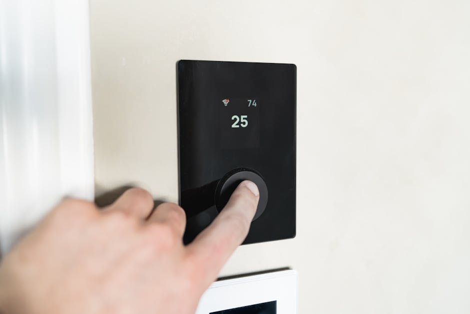 Furnace not blowing hot air: hand adjusting a sleek modern smart thermostat on a wall