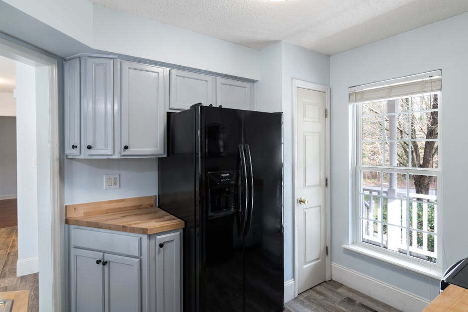 Refrigerator not cooling: sleek black refrigerator in a modern kitchen with large window