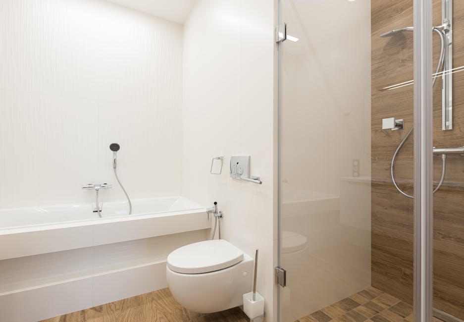 Toilet keeps clogging: shower cabin with glass door and ceramic bathtub and toilet bowl in a spacious bathroom, the typical homeowner setting where a toilet keeps clogging cycle plays out