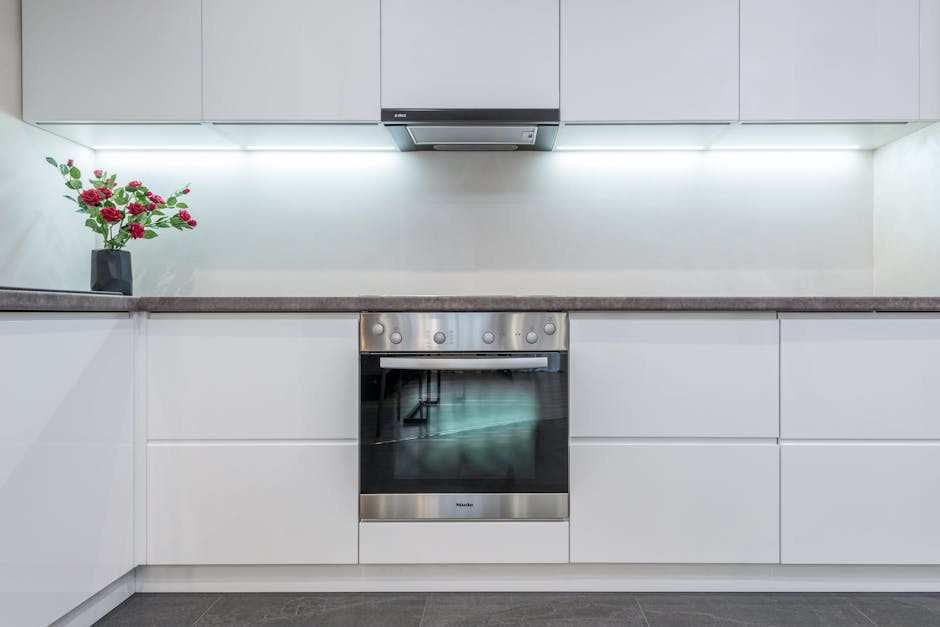 Oven not heating: a sleek built-in chrome electric oven and range hood in a modern white kitchen with minimalist cabinetry