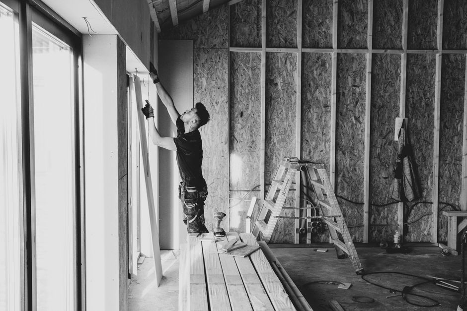 Installer fitting a new replacement window while explaining window replacement cost to a homeowner