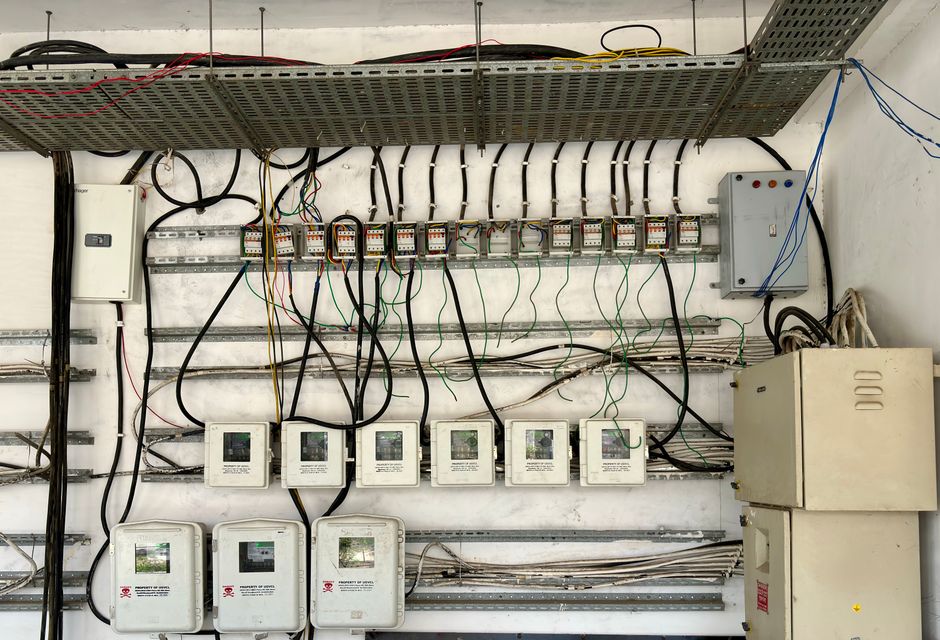 Licensed electrician working on a breaker box while assessing electrical panel upgrade cost for a homeowner