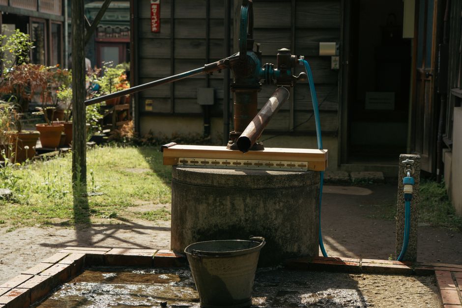 Plumber lowering a new submersible unit into a basement pit while explaining sump pump replacement cost to a homeowner