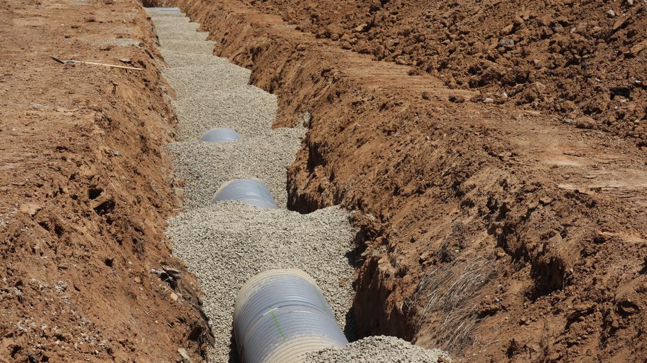 New drainage pipe being installed in an open trench, the core of any sewer line replacement cost